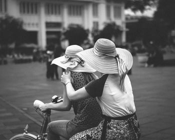 Women wearing hats riding bicycle on street