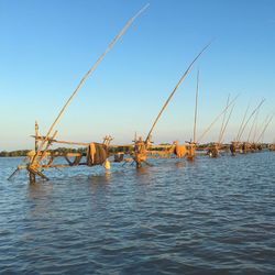 Fishing boats in sea against clear blue sky