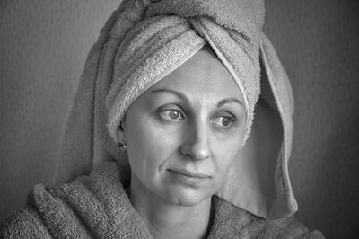 Close-up of thoughtful woman with towel against wall