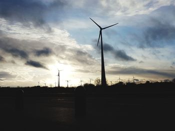 Silhouette windmill on landscape against sky at sunset