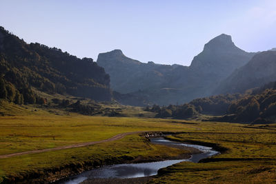 Scenic view of river by mountains against clear sky