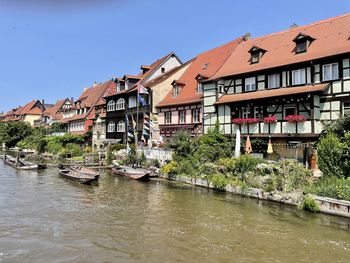 Buildings by river against sky