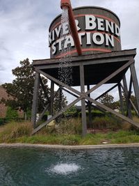 Information sign by bridge against sky