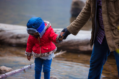 Midsection of father holding hand of daughter while standing outdoors during winter