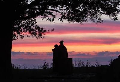 Silhouette couple by tree against sky during sunset