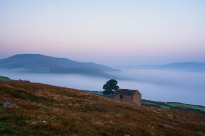 Scenic view of landscape against sky during foggy weather