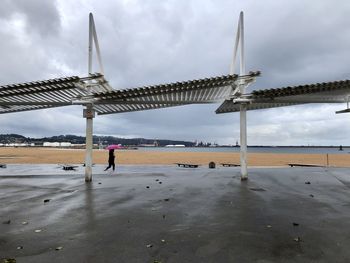 Woman walking on beach against sky