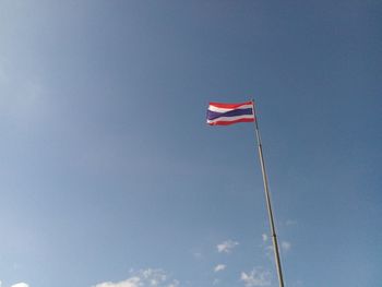 Low angle view of flag against blue sky