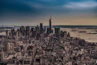 Aerial view of buildings in city against cloudy sky