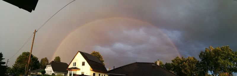 Rainbow over houses against sky