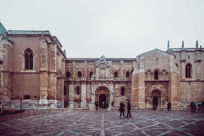 People in front of historic building against clear sky