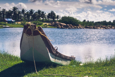 Boat on shore by lake against sky