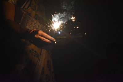 Woman holding sparkler at night