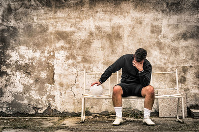 Full length of young man sitting on bench