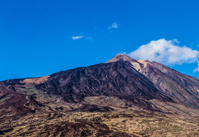 Scenic view of volcanic mountain against blue sky