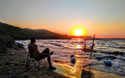 People sitting on chair at beach during sunset