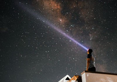 Rear view of man standing against star field at night