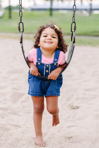 Full length portrait of cute girl swinging at park