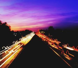 Light trails on road against sky at night