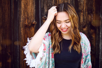 Beautiful young woman standing against wooden wall