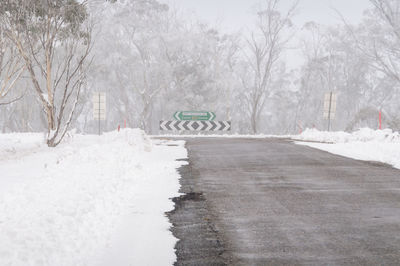 Snow covered road amidst trees during winter