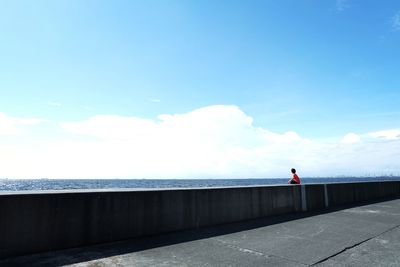 Man standing by sea against blue sky