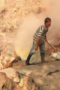 Full length of worker holding sack at construction site