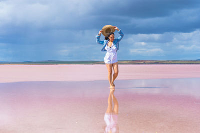 Woman standing at beach against sky