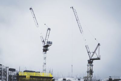 Low angle view of cranes against clear sky