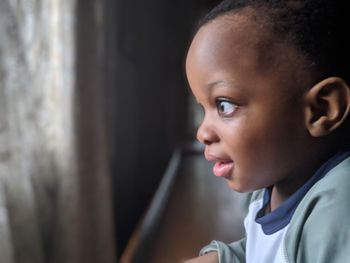 Profile view of thoughtful baby boy looking through window at home