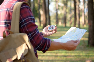 Midsection of man holding map and navigational compass