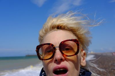 Portrait of young woman wearing sunglasses against clear sky