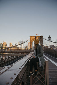 Usa, new york, new york city, female tourist sitting on brooklyn bridge in the morning light