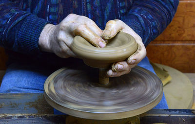 Craftsperson shaping pot on pottery wheel