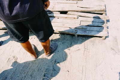 Low section of man standing by wooden raft