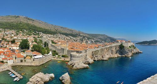 Aerial view of townscape by sea against clear blue sky