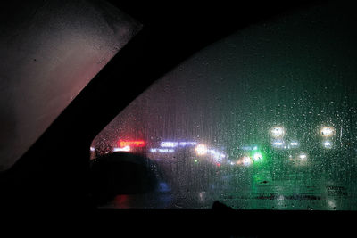 Illuminated street seen through wet car windshield