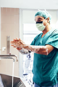 Portrait of young man washing hands in bathroom