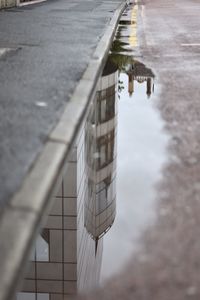 Reflection of building in puddle on street