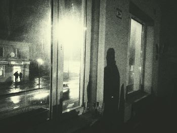 Silhouette man standing by window at night