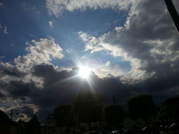 Low angle view of sun shining through clouds