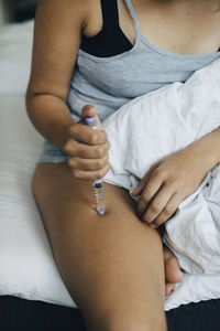 Midsection of man holding hands sitting on bed