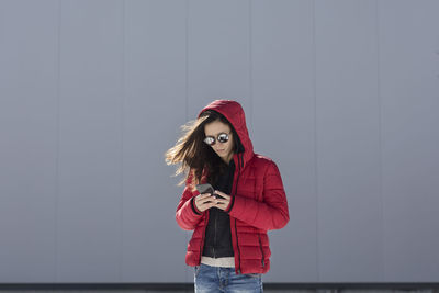 Young woman wearing hat standing against wall