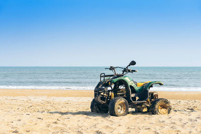 Vintage green atv on the sandy beach. quad atv all terrain vehicle parked on beach, 