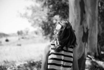 Girl wearing sunglasses looking away while standing at park