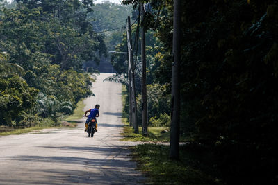 Rear view of man riding motorcycle on road