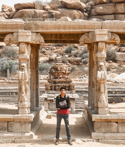 Full length portrait of young woman standing against built structure