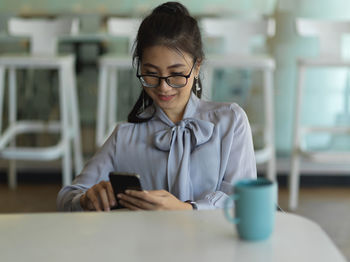 Woman using mobile phone while sitting at office