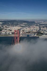 Bridge over river amidst buildings in city against sky