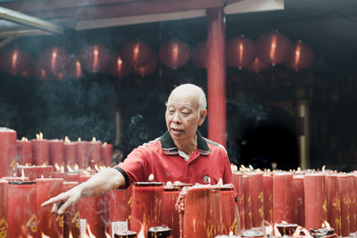 Man pointing by candles in temple